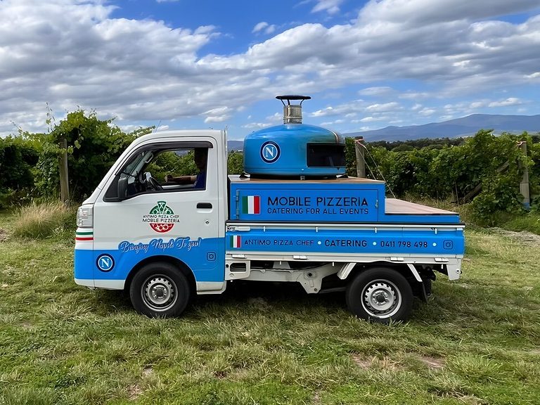 Antimo Pizza Chef's blue and white mobile pizzeria truck parked by a vineyard