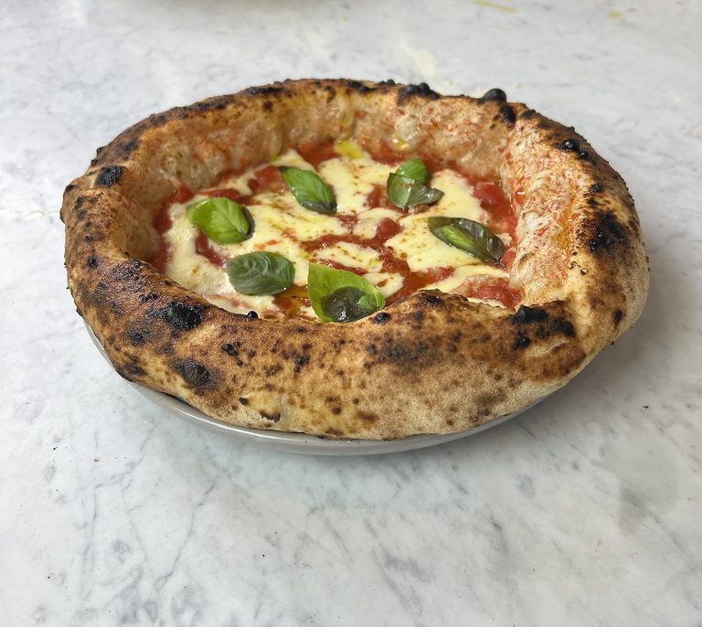 Margherita pizza with fresh basil and a puffy, leopard-spotted crust, pizza catering Melbourne