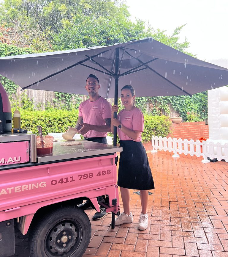 Our pink pizza truck serving under a big umbrella on a rainy day in Sydney