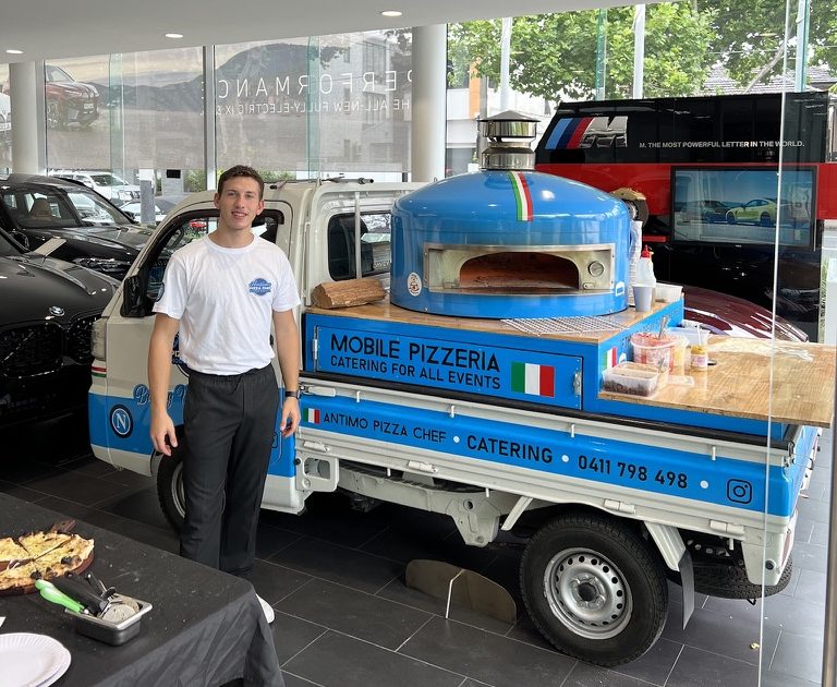 The blue Antimo Pizza Chef truck set up inside a car showroom for a corporate event