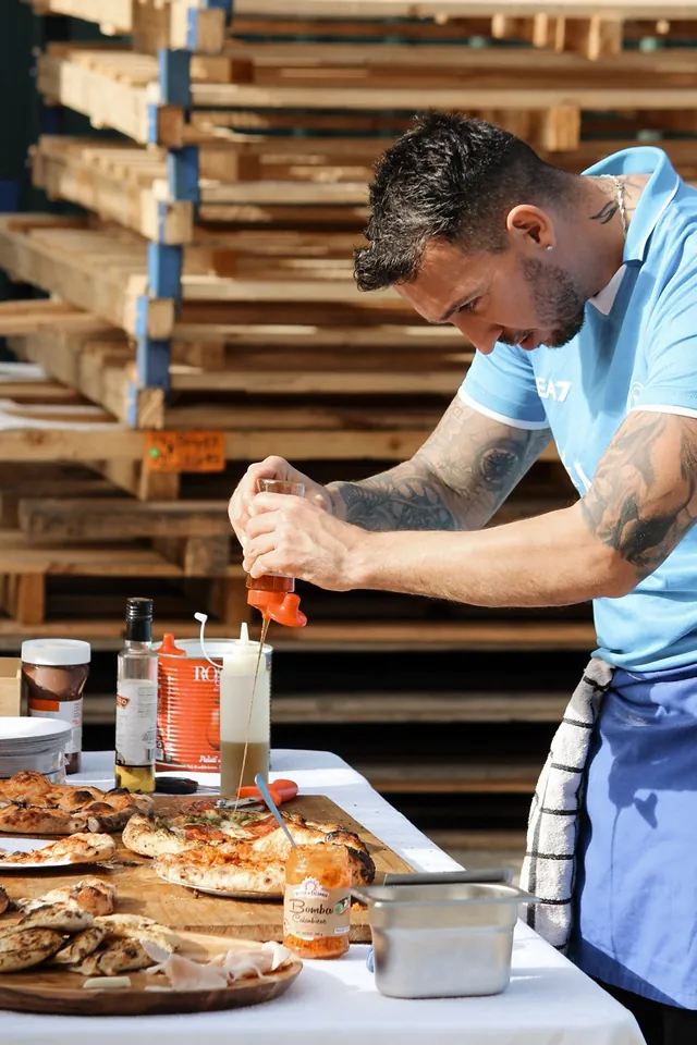 Our chef saucing fresh pizzas on the serving table