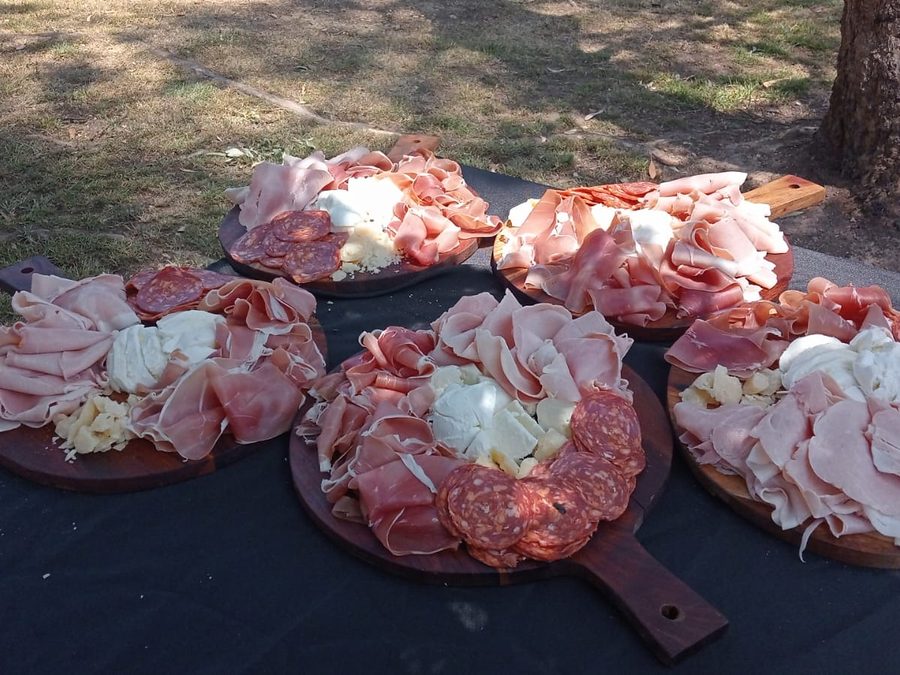 Five antipasto boards with cured meats and burrata on a black table cloth, ready for guests
