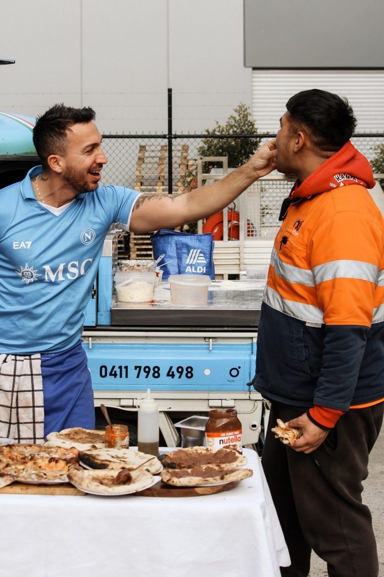 Our chef sharing a slice of pizza with a worker in hi-vis at a workplace event
