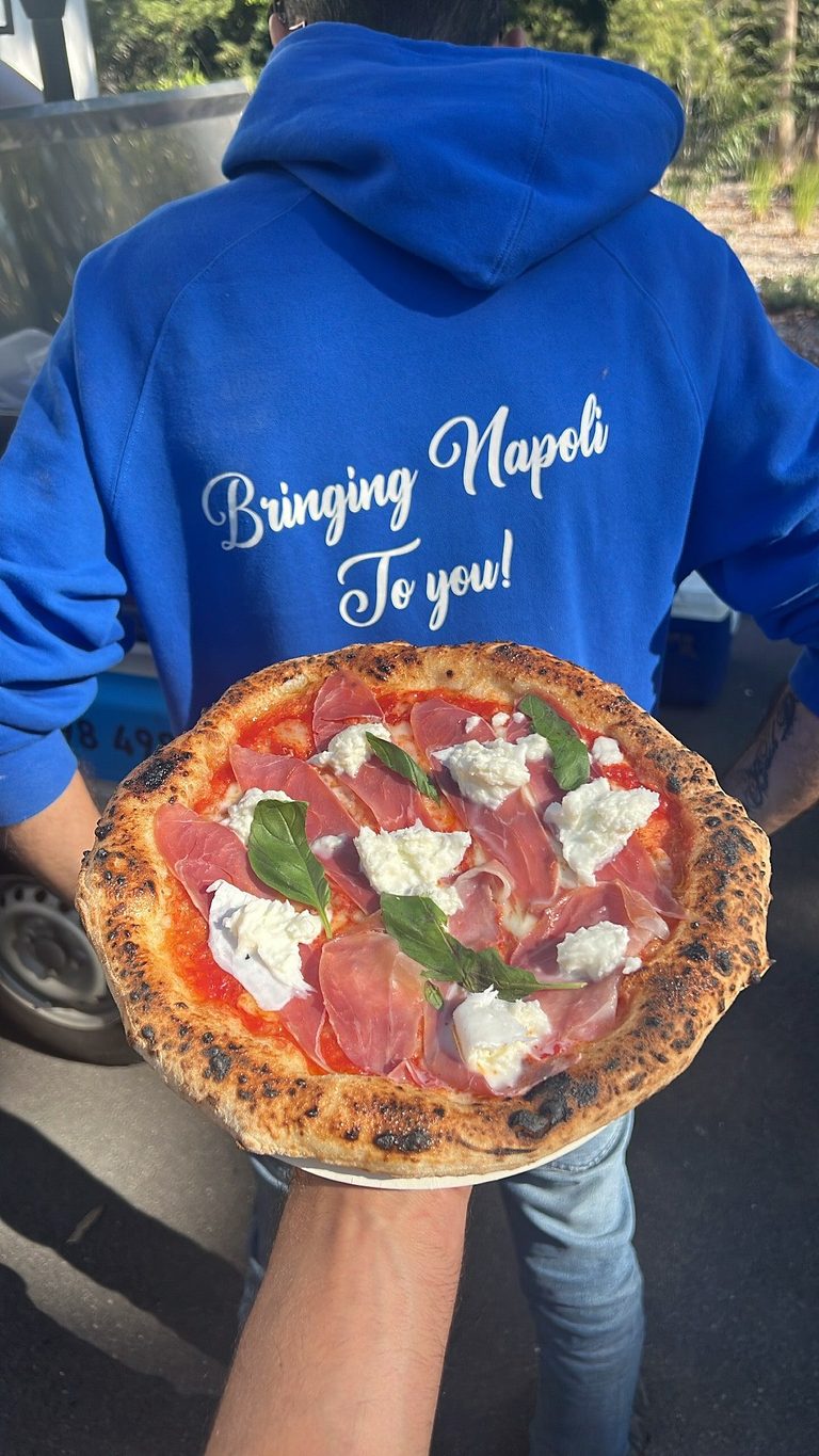 Our chef in a blue Antimo Pizza Chef hoodie holding a pizza