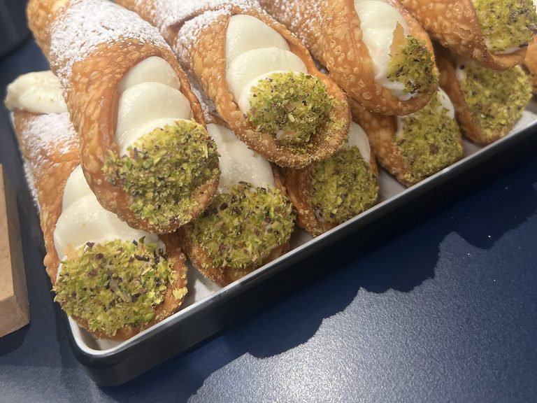 Fresh Sicilian cannoli filled with sweet ricotta, dipped in crushed pistachios and dusted with icing sugar