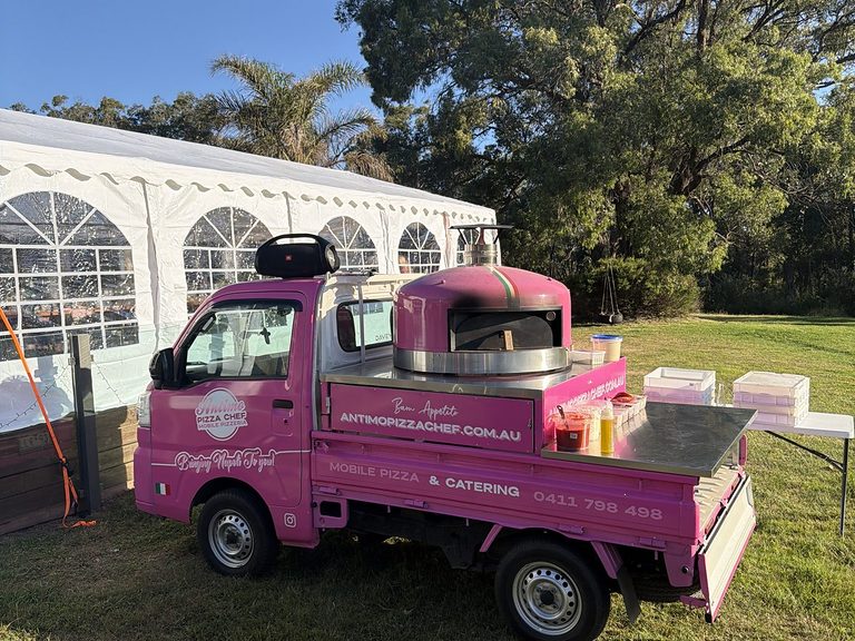 Lady Oscar 1.0, our pink mobile pizzeria truck parked on the lawn beside a white wedding marquee