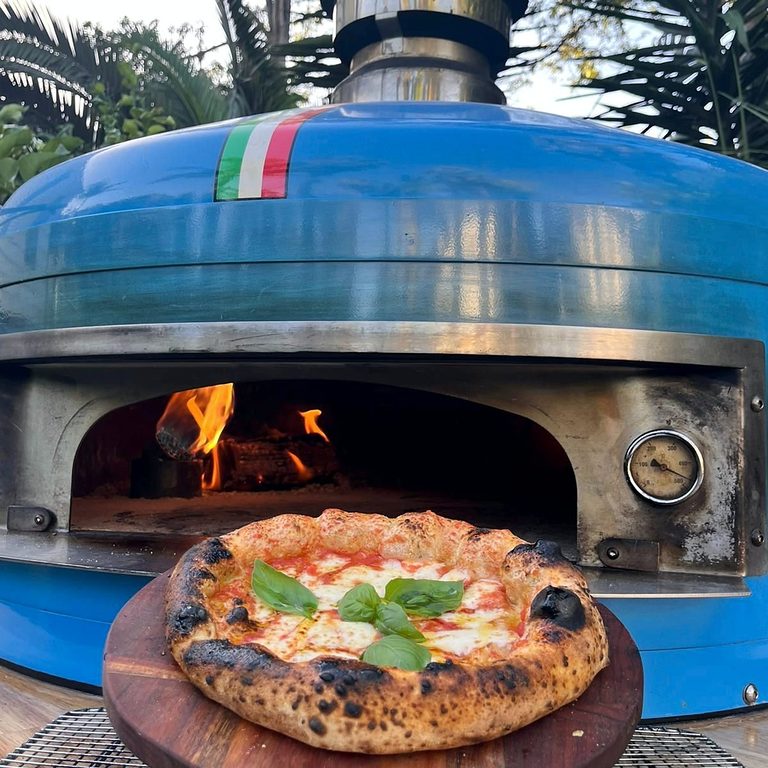 Wood-fired pizza coming out of the oven at a party