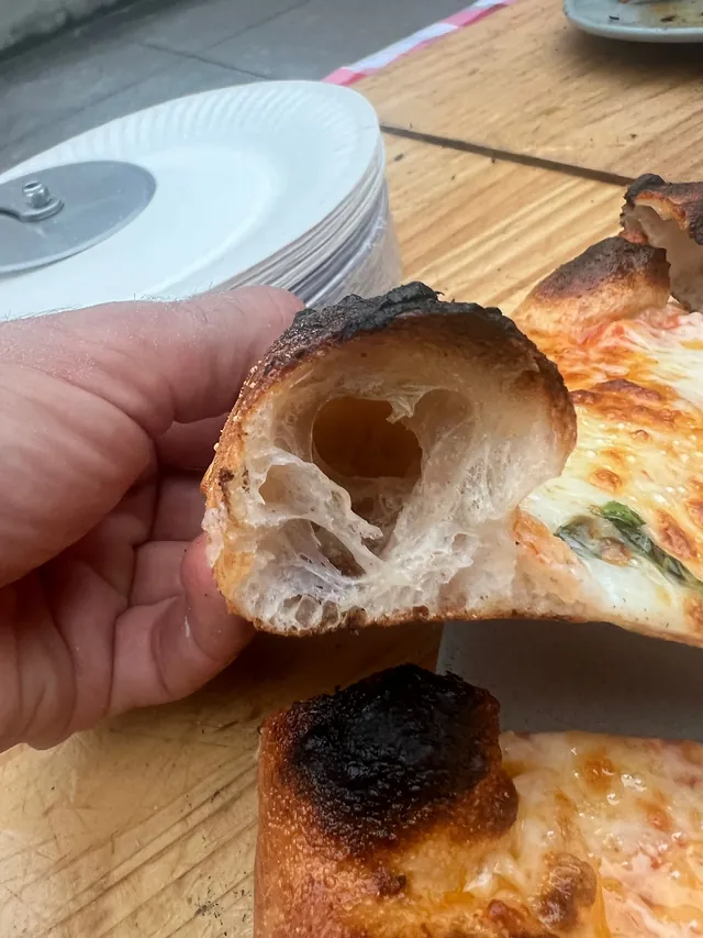 Airy Neapolitan pizza crust cut open to show the light crumb