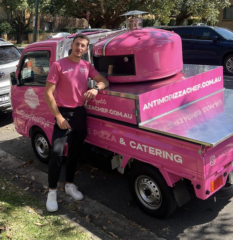 Matteo the Pizza Singer standing beside the pink Antimo Pizza Chef mini truck and wood-fired oven in Sydney
