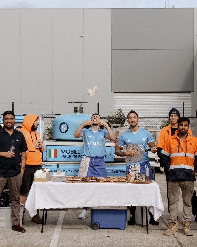 Workplace team in hi-vis at a corporate pizza catering event with the Antimo truck