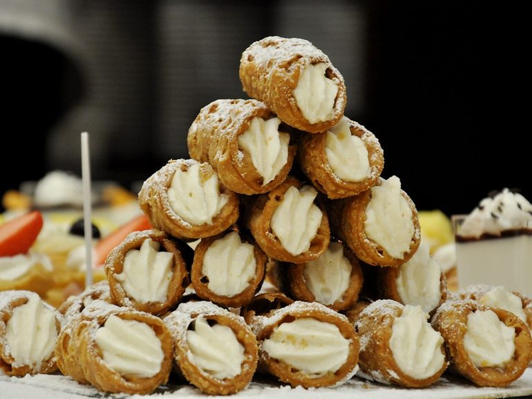 Golden Sicilian cannoli filled with sweet ricotta and dusted with icing sugar