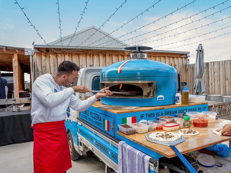 Our chef cooking at the blue wood-fired oven on the truck, pizza catering Northern Beaches
