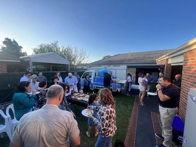 Guests enjoying wood-fired pizza at an evening backyard party