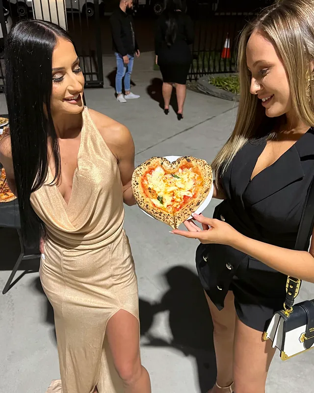 Guests holding a fresh wood-fired pizza