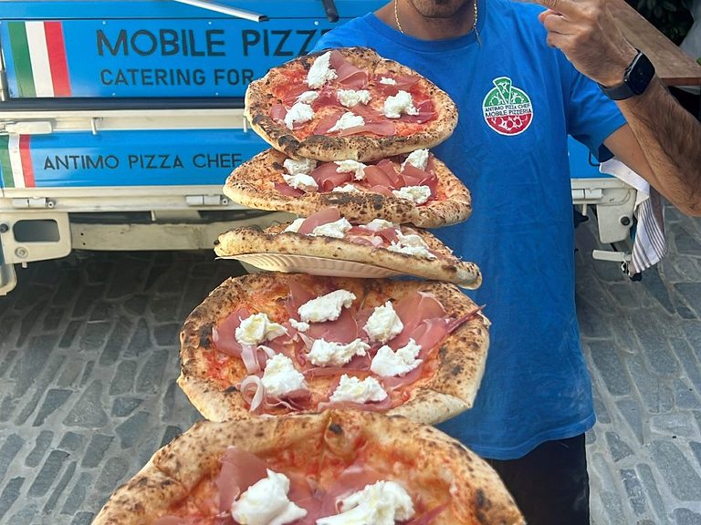 Our chef carrying a stack of fresh wood-fired pizzas