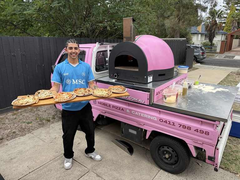 Lady Oscar 1.0, the pink Antimo Pizza Chef pizza truck, with our chef holding a board of fresh pizzas