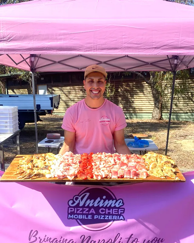 Our chef under the pink marquee with trays of fresh pizza