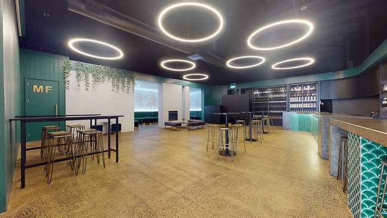 Inside The Palms Cremorne warehouse venue with circular ceiling lights and a long bar
